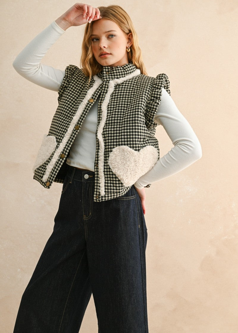 Three-quarter front view of the Rosie gingham puffer vest in black, layered over a long sleeve top