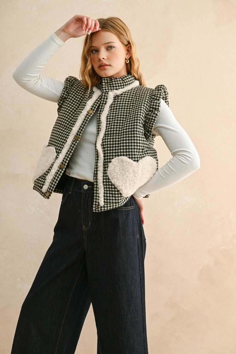 Three-quarter front view of the Rosie gingham puffer vest in black, layered over a long sleeve top