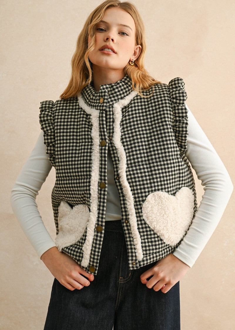 Model wearing the Rosie Gingham Sherpa Puffer Vest in black, front portrait view with sherpa heart pockets