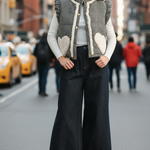 Outdoor street-style photo of the Rosie gingham sherpa puffer vest in black, front view while walking