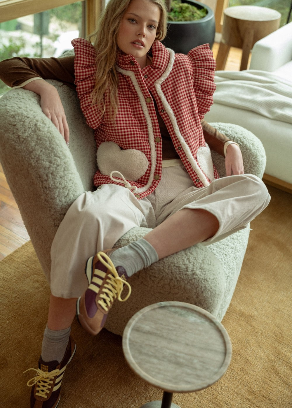 Cozy indoor portrait of model wearing the Rosie Gingham Sherpa Puffer Vest in red with sherpa heart pockets