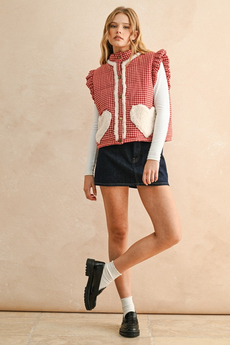 Full-body photo of model walking in the red gingham sherpa puffer vest styled with a skirt and long sleeve top