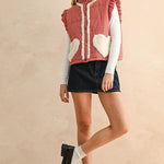 Full-body photo of model walking in the red gingham sherpa puffer vest styled with a skirt and long sleeve top