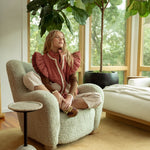 lifestyle view of model in the red gingham sherpa puffer vest sitting in a chair, full outfit visible