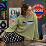 Lifestyle image of model wearing the Sardine Balloon Sleeve Sweater in olive inside a record store