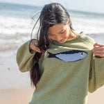 Outdoor lifestyle photo of model wearing the Sardine Balloon Sleeve Sweater in olive near the beach