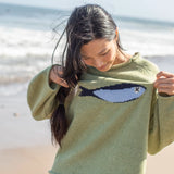 Outdoor lifestyle photo of model wearing the Sardine Balloon Sleeve Sweater in olive near the beach