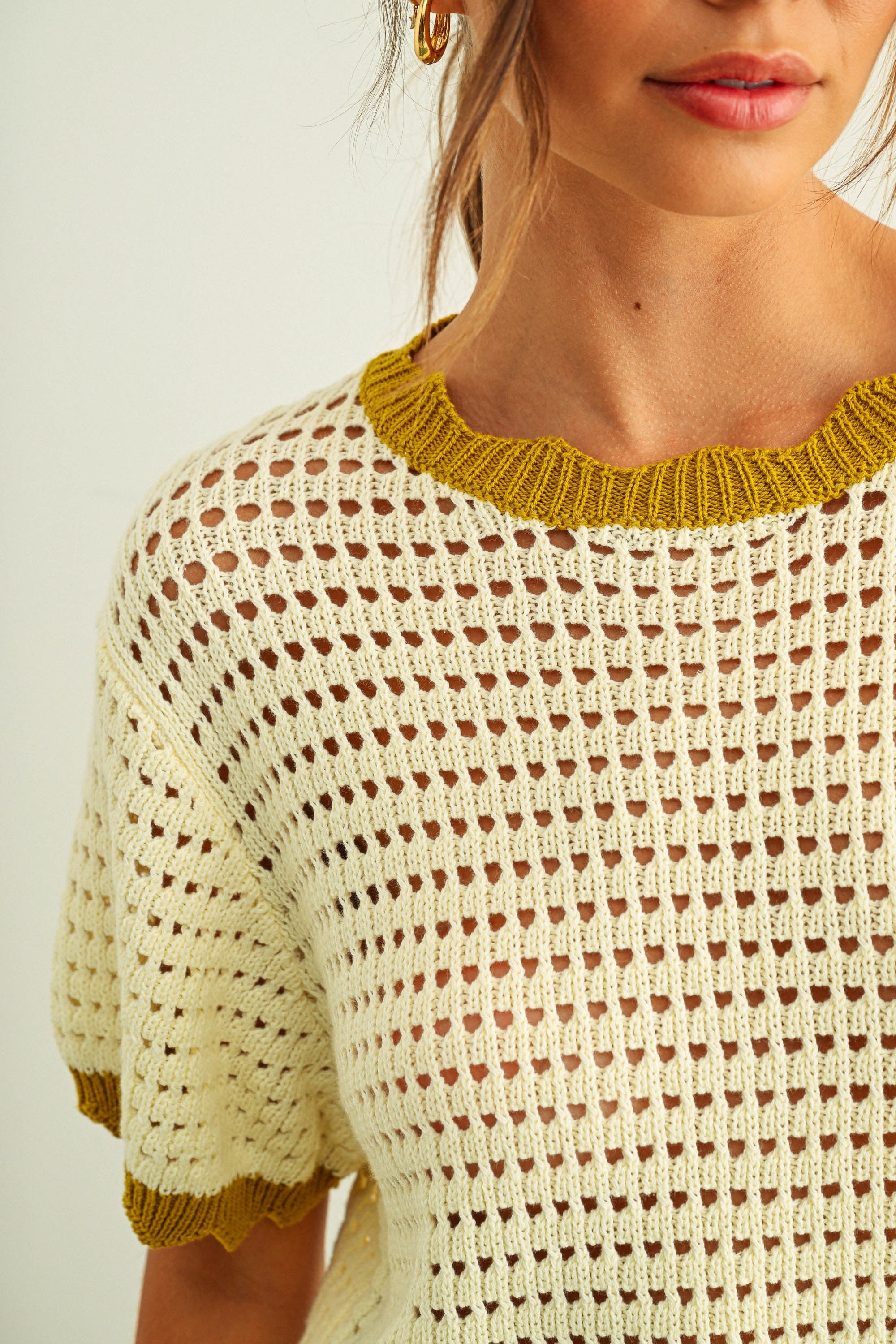 Close-up of scalloped neckline and mesh knit texture on cream cotton short sleeve top
