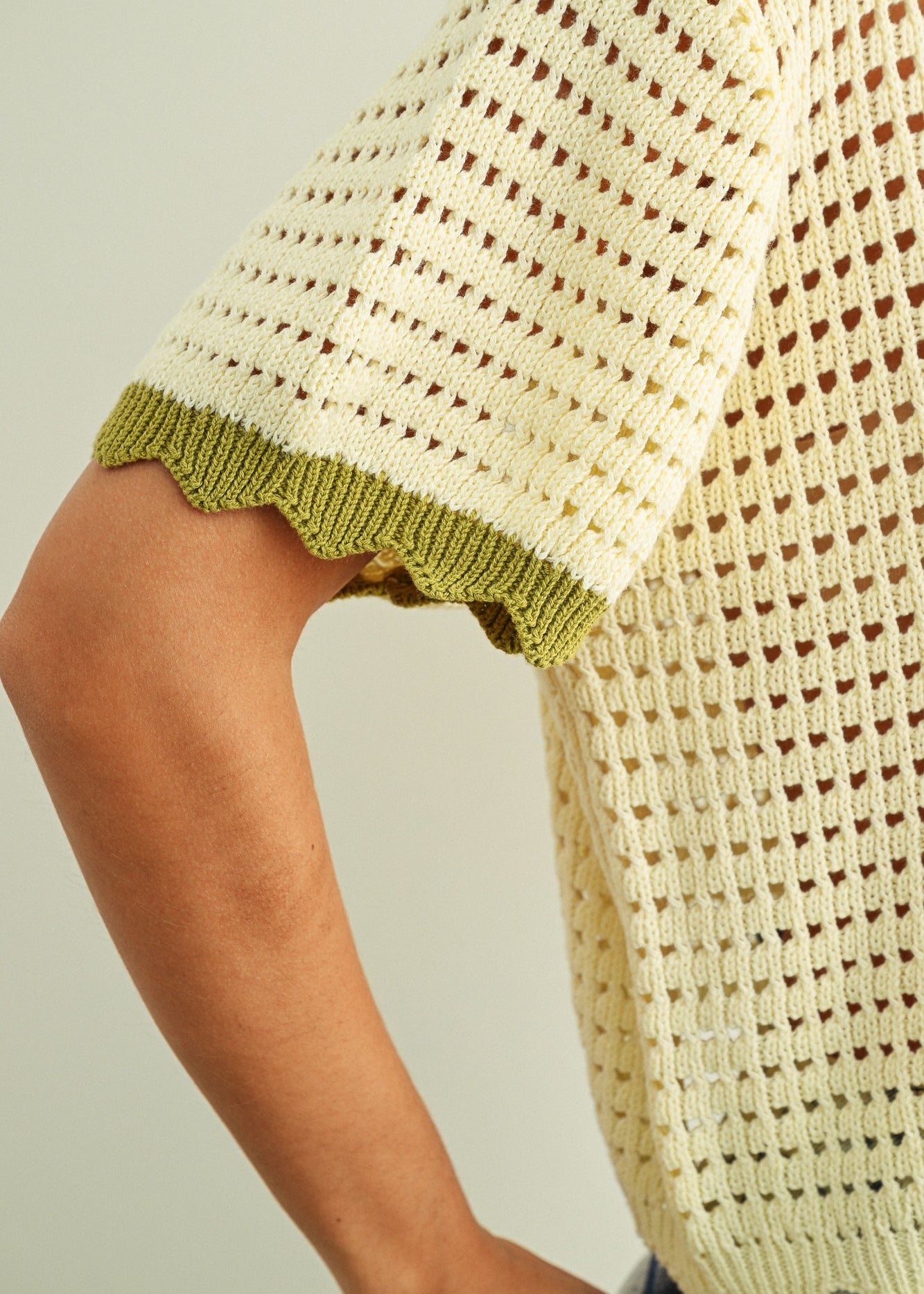 Close-up of breathable mesh knit pattern on cream cotton short sleeve top with sage trim