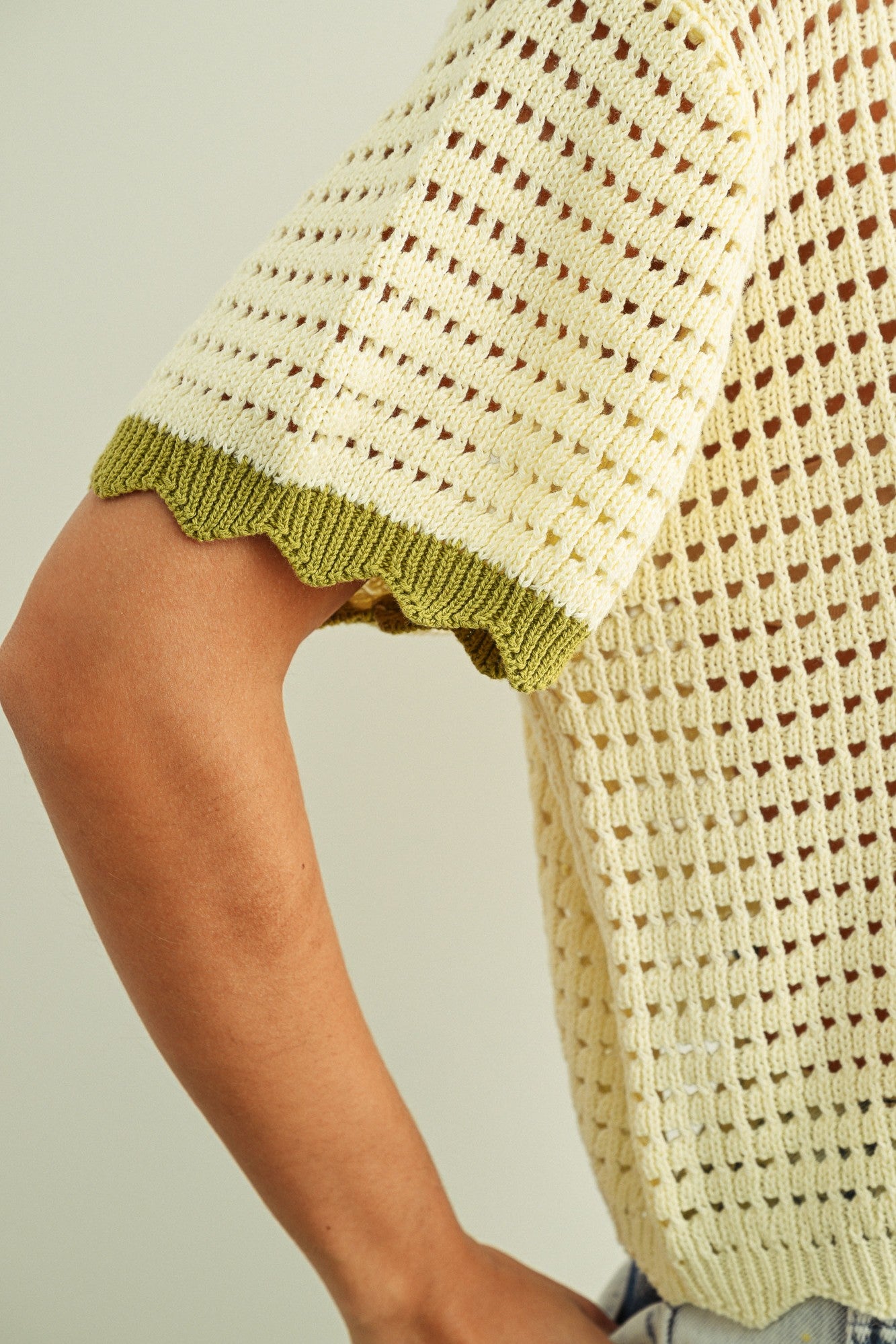Close-up of breathable mesh knit pattern on cream cotton short sleeve top with sage trim