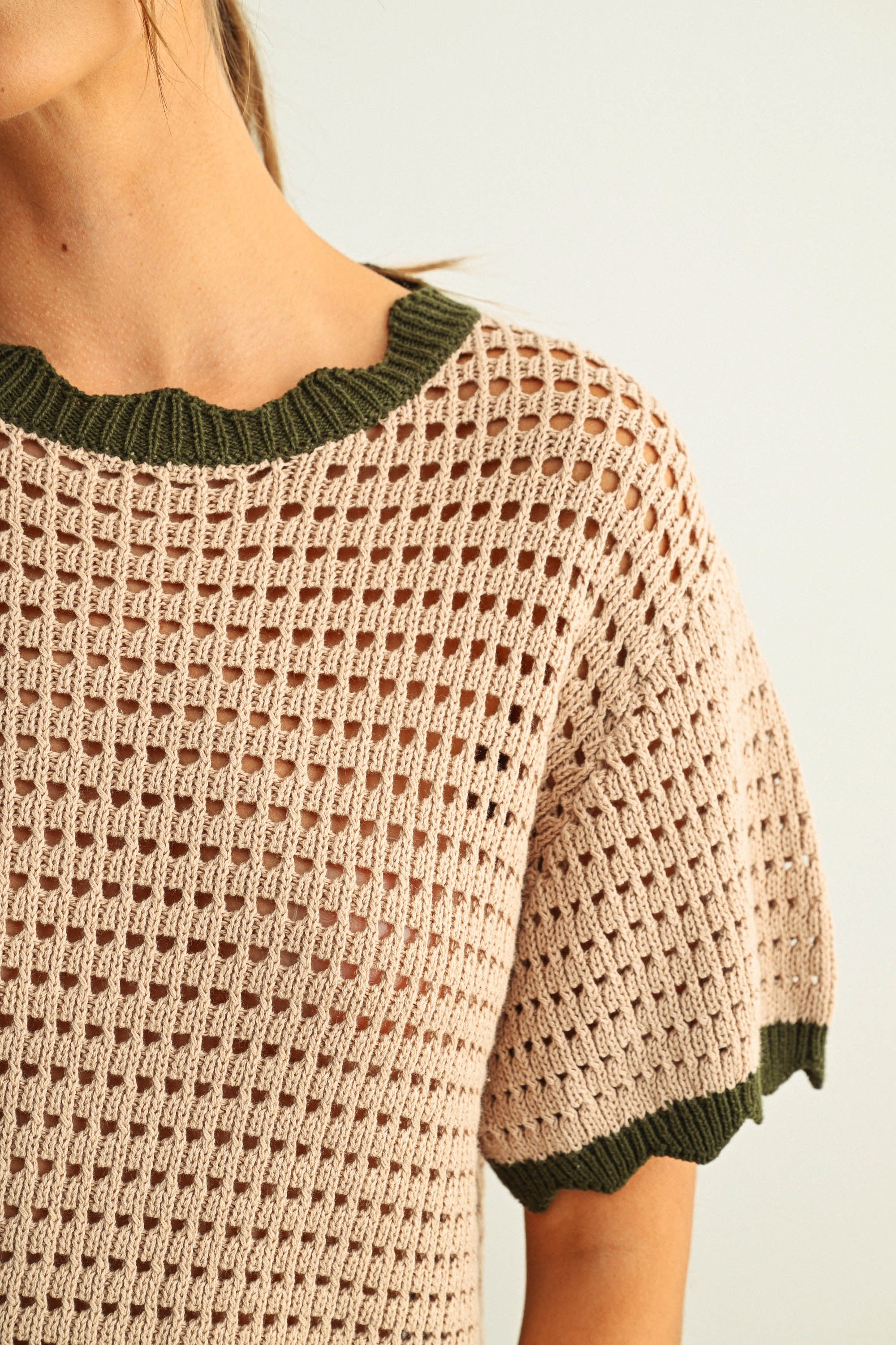Close-up of breathable mesh knit texture on tan cotton short sleeve top with olive trim