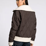 Back view of the brown quilted puffer jacket showing quilted pattern and knit trim at hem