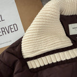 Close-up of the All Deserved label and knit collar trim on the brown puffer jacket