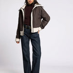 Full-body front view of model wearing the brown button-down quilted puffer jacket with jeans