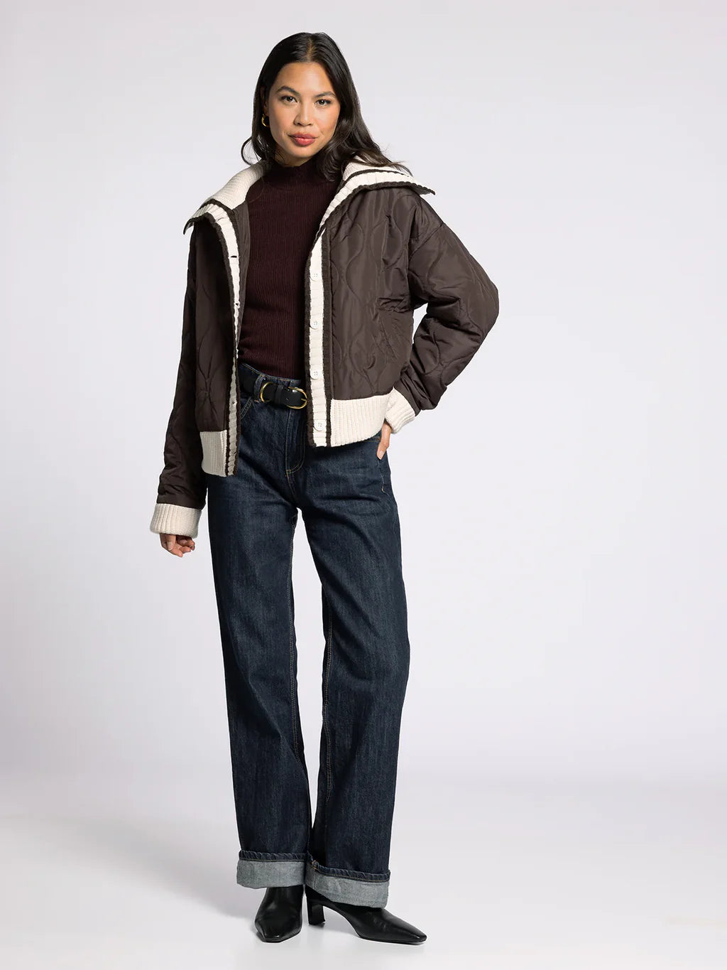Full-body front view of model wearing the brown button-down quilted puffer jacket with jeans