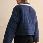 Back view of the blue quilted jacket showing the relaxed fit and puffer silhouette