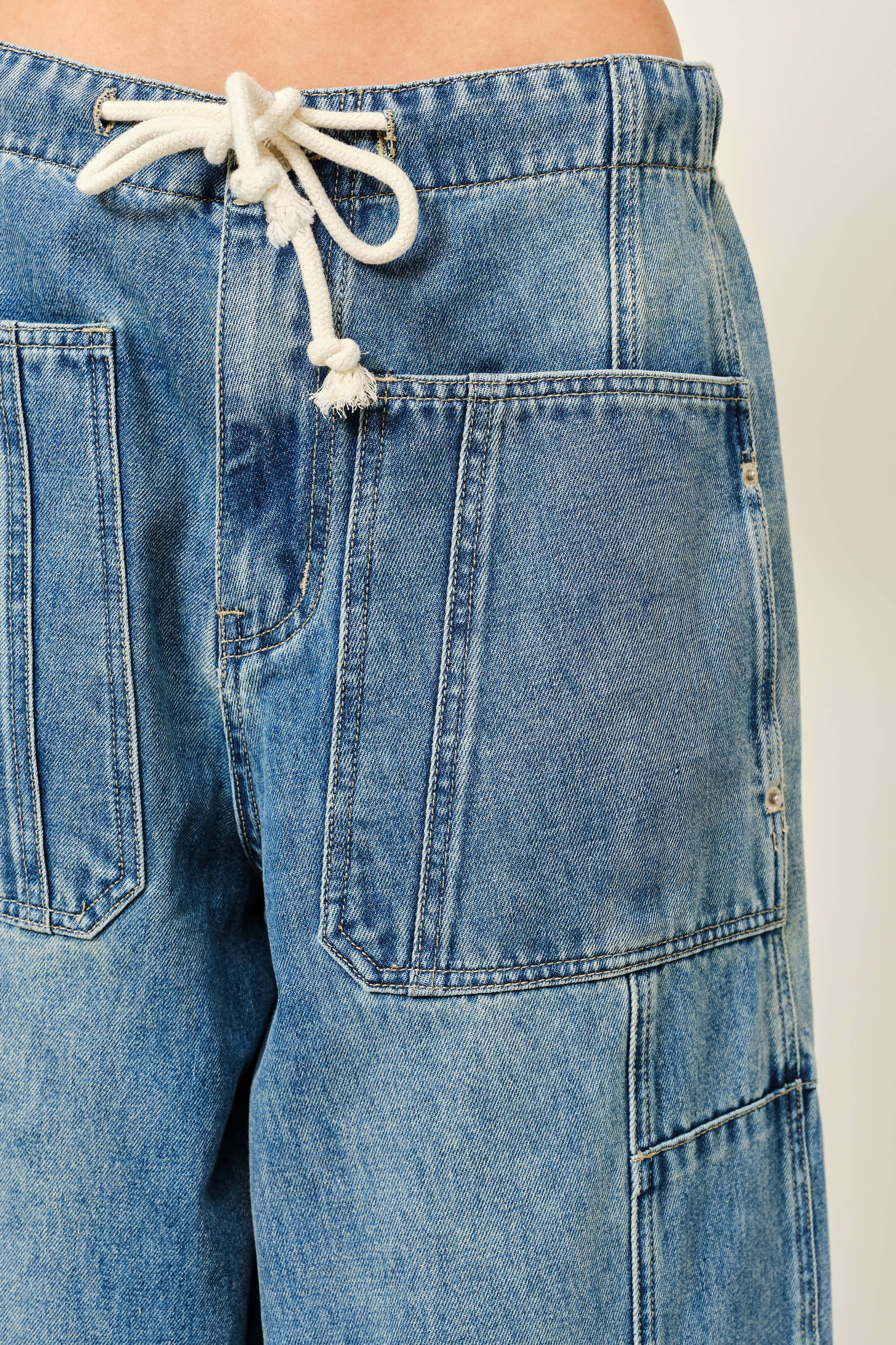 Close-up of Silverton medium wash barrel jeans featuring adjustable drawstring waist and patch pockets