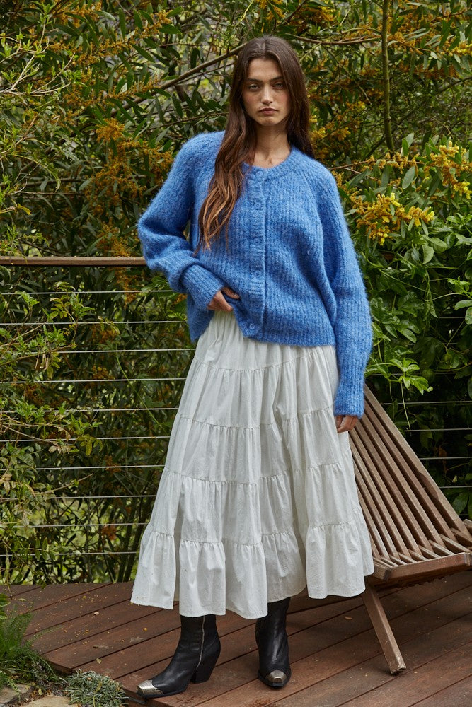 Full-body outfit: cobalt blue button cardigan styled with a white tiered midi skirt