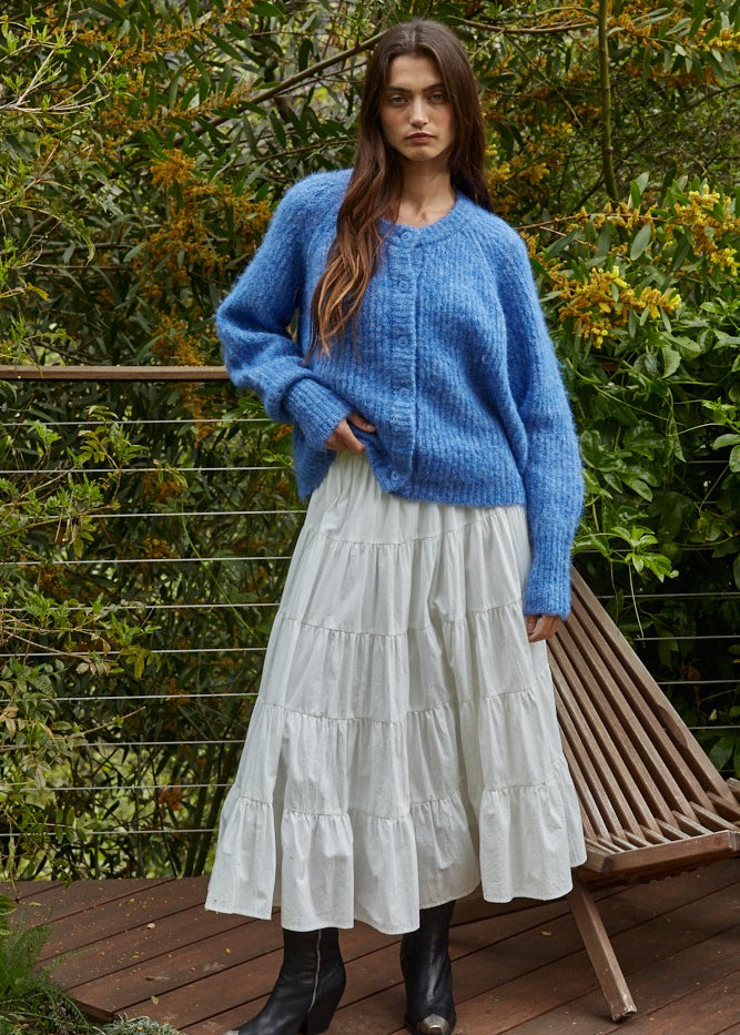 Full-body outfit: cobalt blue button cardigan styled with a white tiered midi skirt