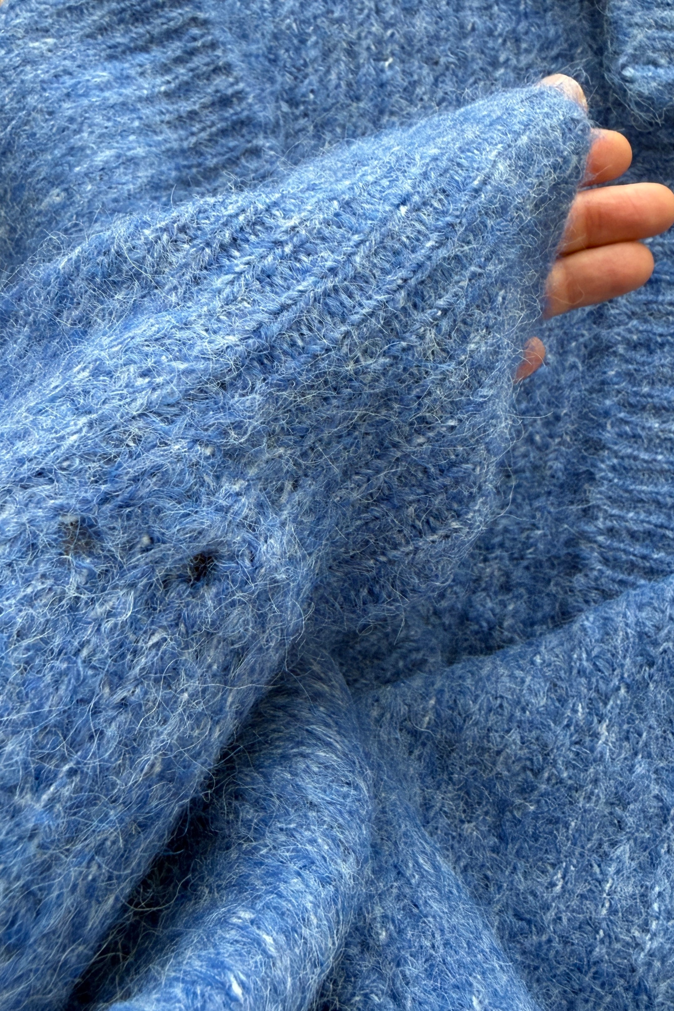 Close-up of sleeve detailing on the cobalt blue Skyline cardigan, subtle distressed finish