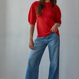Full-body front view of the red short sleeve balloon sleeve sweater styled with blue jeans