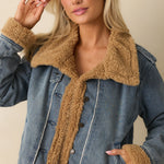 Woman wearing a teddy-lined denim jacket with sherpa collar and trim — cozy medium-wash outerwear for fall.