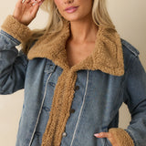 Woman wearing a teddy-lined denim jacket with sherpa collar and trim — cozy medium-wash outerwear for fall.