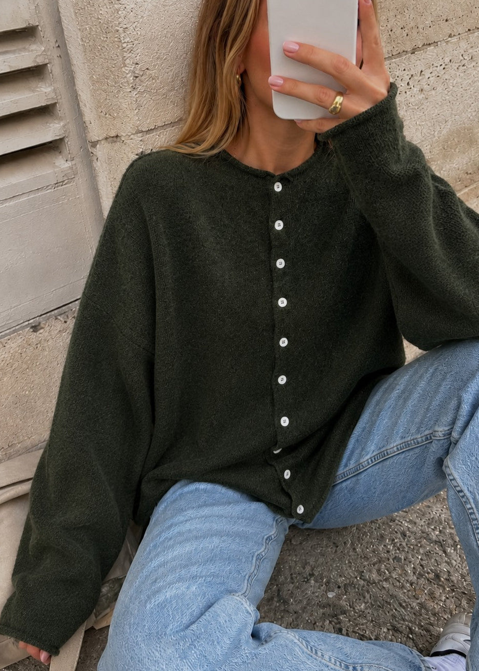 Woman wearing the Things Between Piper Cardigan in dark hunter green