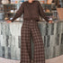 Woman wearing Trudy chocolate plaid wide-leg pants inside a coffee shop
