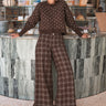 Woman wearing Trudy chocolate plaid wide-leg pants inside a coffee shop
