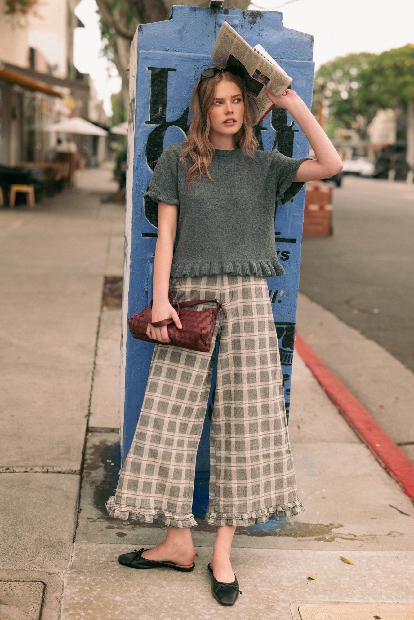 Woman wearing Trudy grey plaid wide-leg pants with a sweater and flats