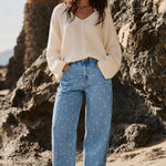 Woman wearing Truro High Rise Barrel Jeans in Denim Polka Dot in a beach lifestyle photo