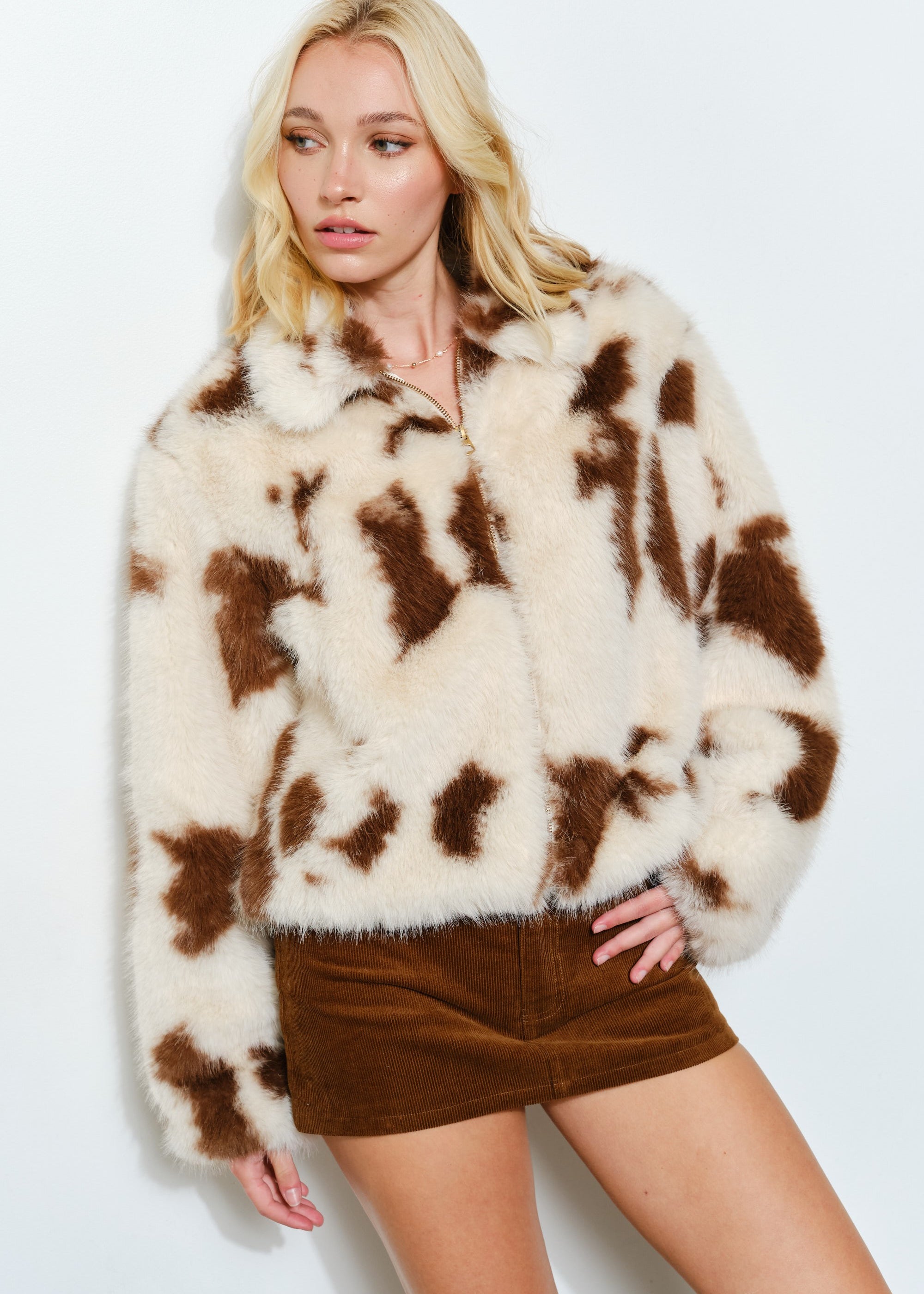 Front portrait of model wearing the Unreal cow print faux fur jacket