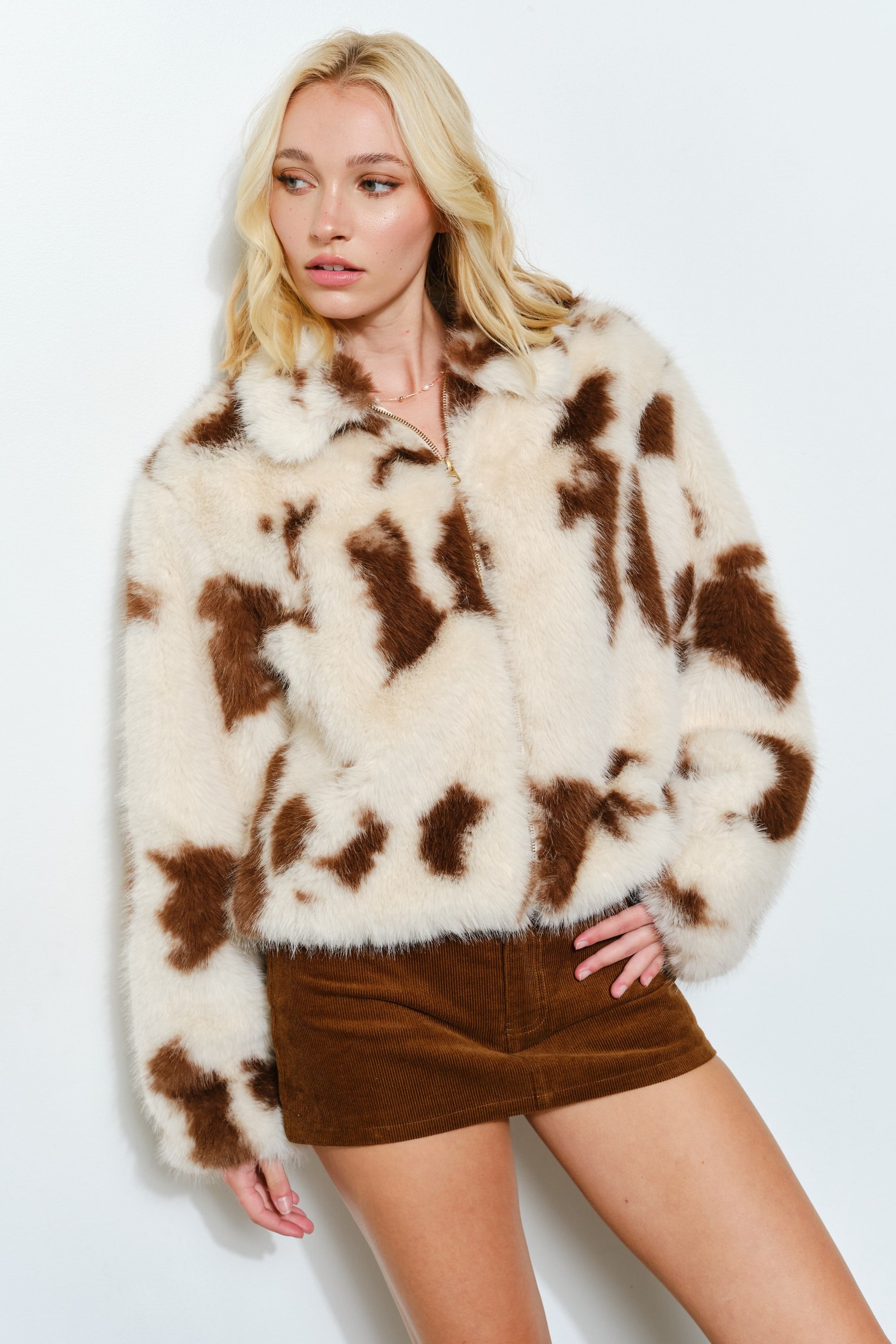 Front portrait of model wearing the Unreal cow print faux fur jacket