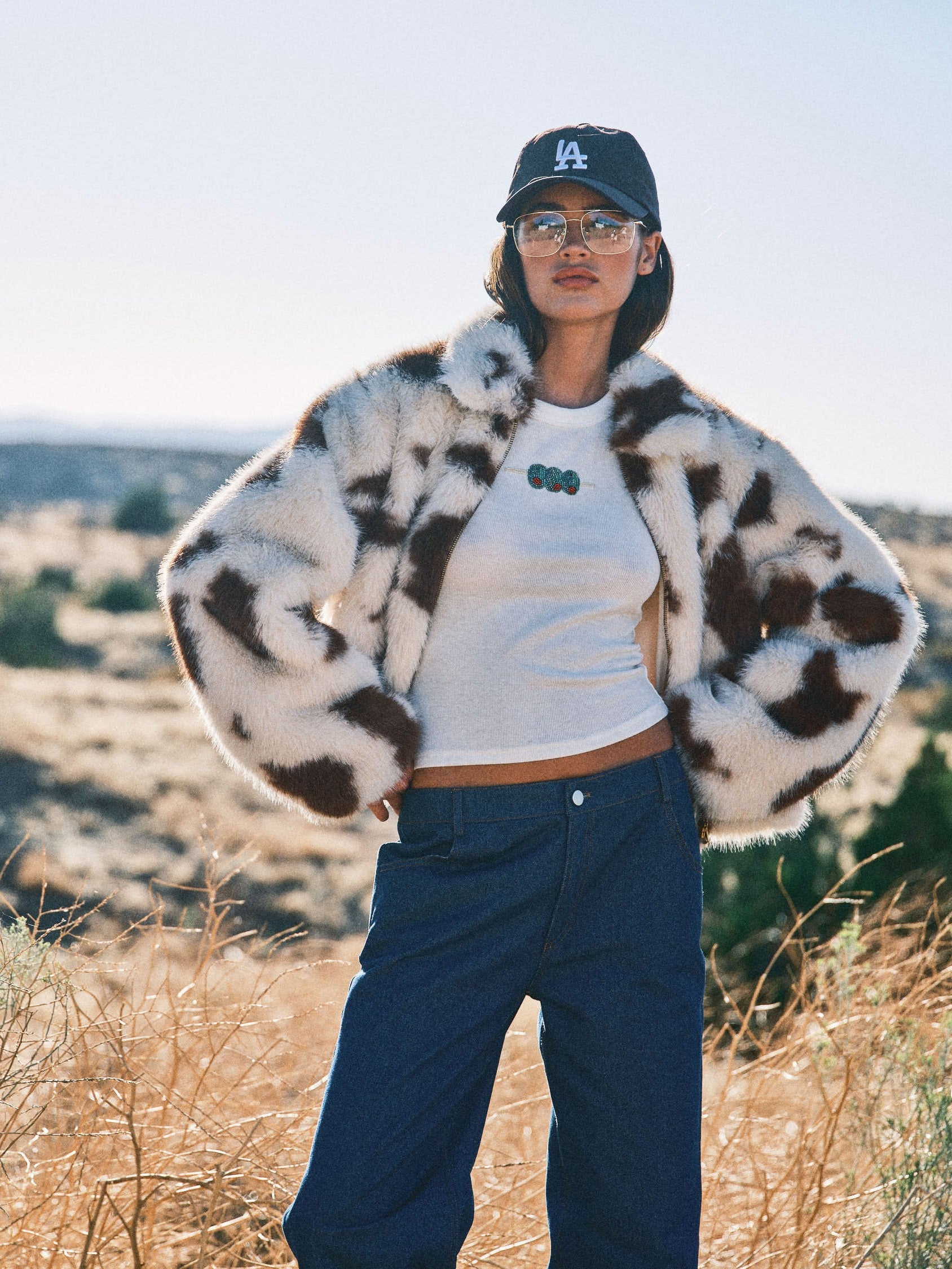 Outdoor lifestyle image of model wearing the cow print faux fur jacket in a desert setting