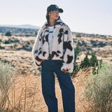 Lifestyle photo of the Unreal cow print faux fur jacket styled casually outdoors