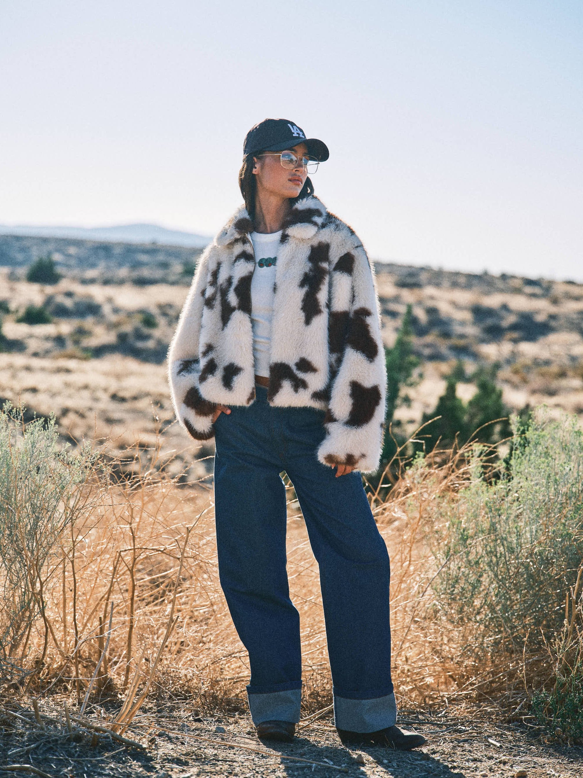 Lifestyle photo of the Unreal cow print faux fur jacket styled casually outdoors