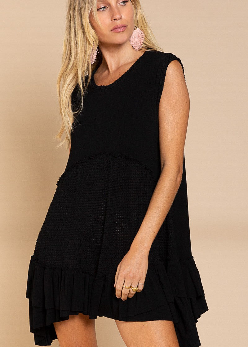 Angled front view of Wildest Rose black tunic dress showing flowy ruffle hem