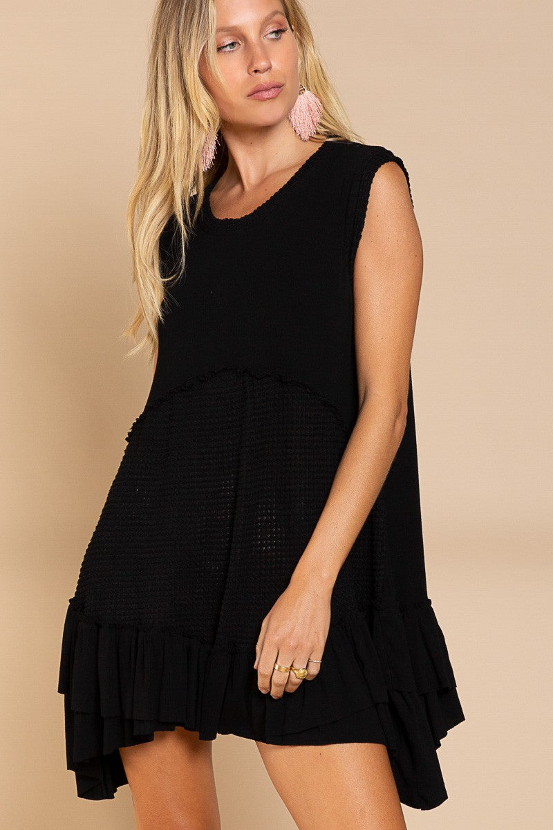 Angled front view of Wildest Rose black tunic dress showing flowy ruffle hem