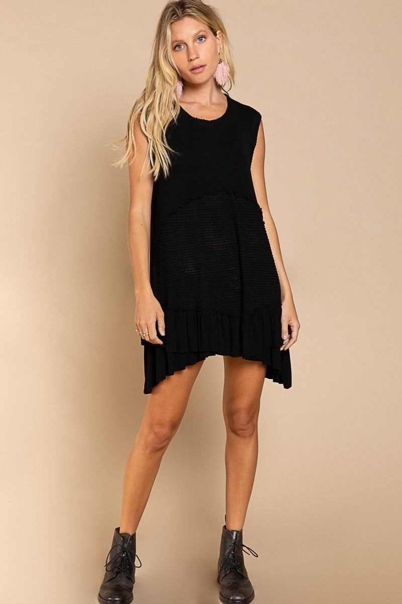 Model is wearing Wildest Rose tunic dress in black with babydoll silhouette and ruffle hem - front view